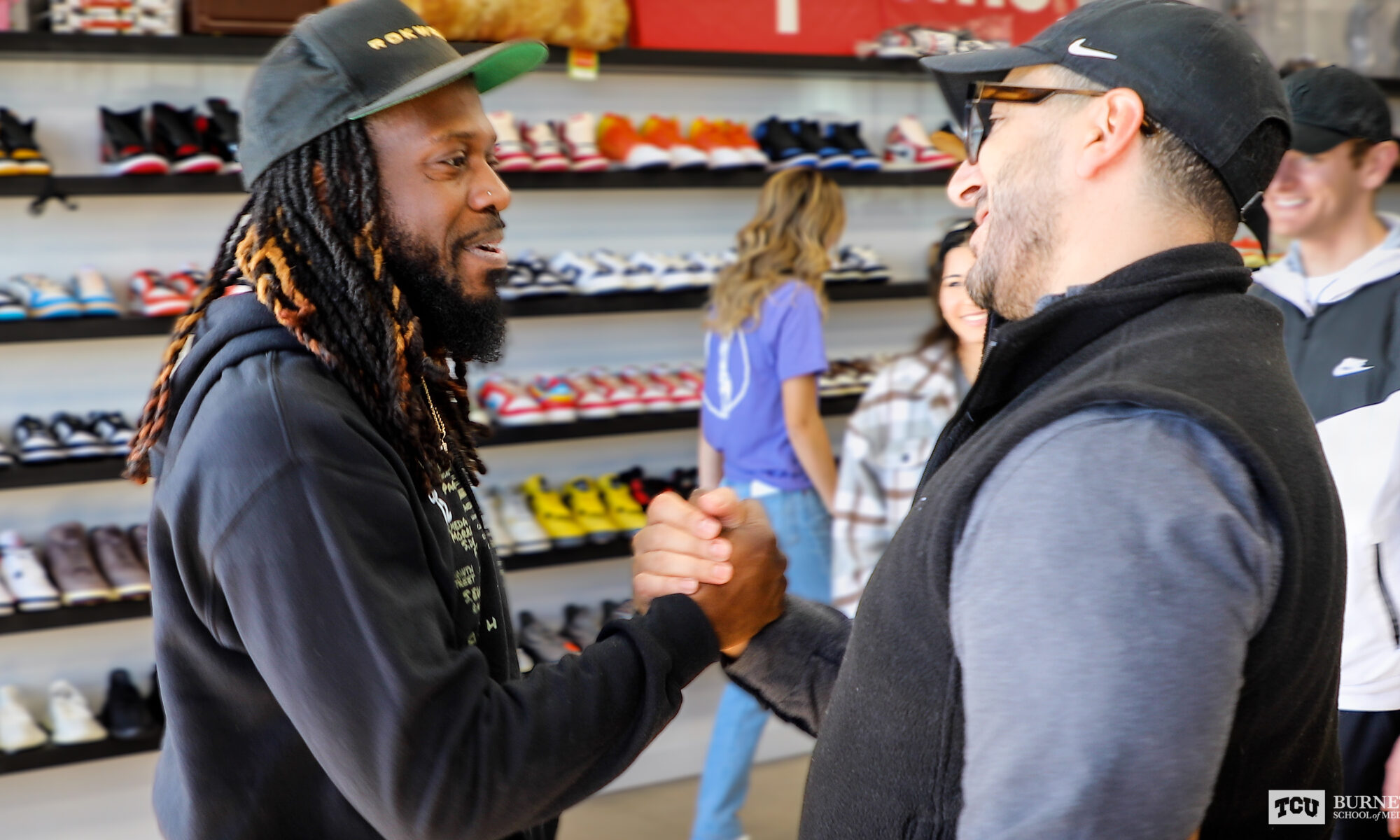 Michael Rose and Sam Sayed, MS4, Co2024 share a handshake in a shoe store in Fort Worth.